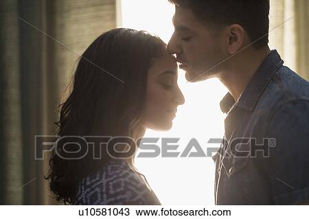 Stock Image - Young couple kissing in sunlight. Fotosearch