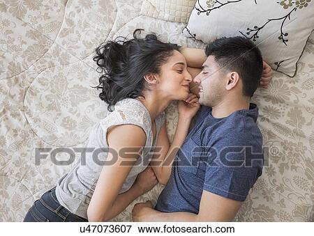 Stock Photo - Young couple lying on bed. Fotosearch