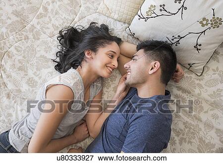 Young couple lying on bed View Large Photo Image Stock Photo - Young couple lying on bed. Fotosearch