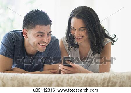 Young couple relaxing on bed View Large Photo Image Stock Photograph - Young couple relaxing on bed. Fotosearch
