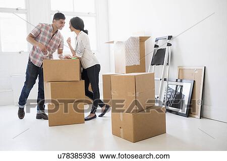 Young couple standing among boxes in new home View Large Photo Image Stock Photo - Young couple standing among boxes in new home. Fotosearch