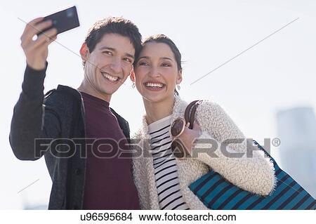 Picture - Young couple taking selfie. Fotosearch