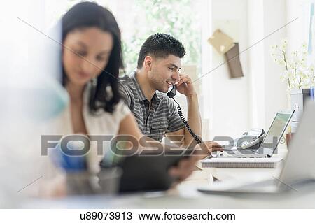 Young man and woman working in office View Large Photo Image Stock Image - Young man and woman working in office. Fotosearch