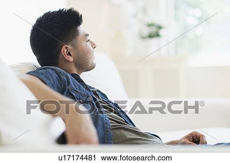 Young man relaxing on sofa View Large Photo Image Stock Image - Young man relaxing on sofa. Fotosearch