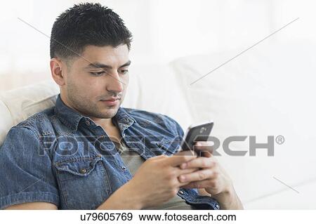 Stock Photo - Young man using mobile phone. Fotosearch