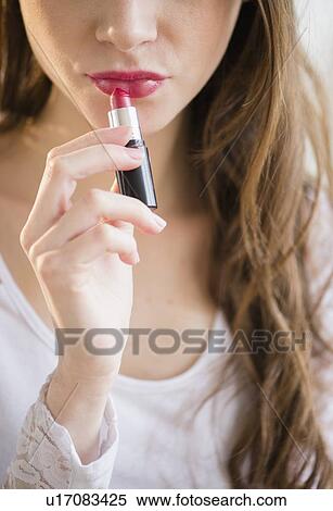 Young woman applying lipstick View Large Photo Image Stock Photography - Young woman applying lipstick. Fotosearch