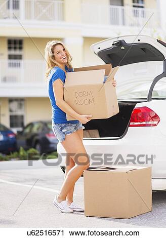 Young woman carrying box from car into her new house View Large Photo Image Stock Image - Young woman carrying box from car into her new house. Fotosearch