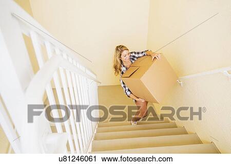 Young woman carrying box in her new house View Large Photo Image Stock Image - Young woman carrying box in her new house. Fotosearch