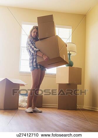 Young woman carrying boxes in her new house View Large Photo Image Stock Image - Young woman carrying boxes in her new house. Fotosearch