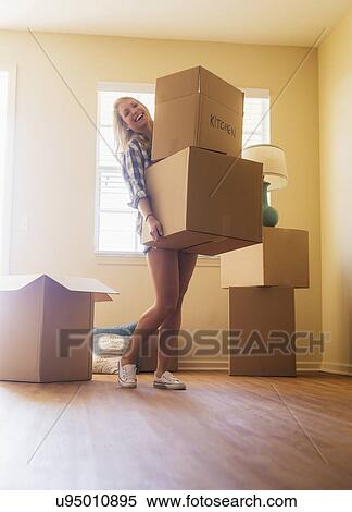 Young woman carrying boxes in her new house View Large Photo Image Stock Photography - Young woman carrying boxes in her new house. Fotosearch