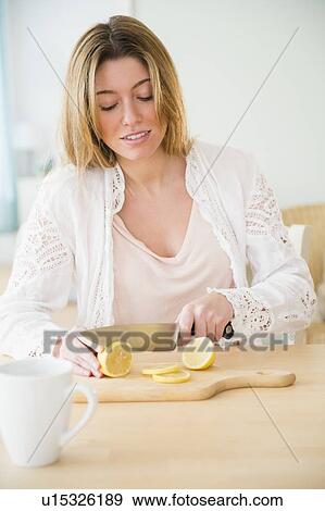 Stock Photo - Young woman cutting lemon. Fotosearch