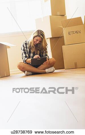 Stock Photo - Young woman during moving into new house. Fotosearch