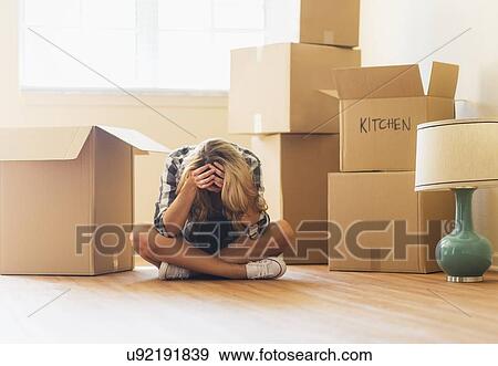 Stock Photo - Young woman during moving into new house. Fotosearch