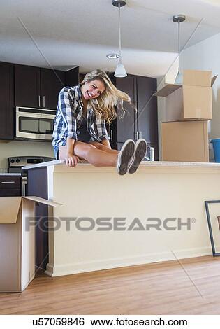 Stock Photograph - Young woman during moving into new house. Fotosearch