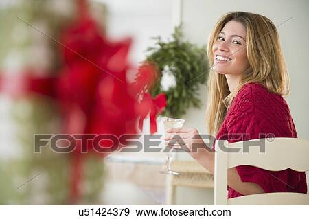 Stock Photo - Young woman holding champagne flute at christmas. Fotosearch
