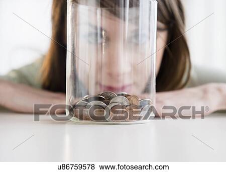 Young woman looking at coins in jar View Large Photo Image Stock Photo - Young woman looking at coins in jar. Fotosearch