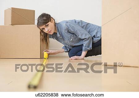 Stock Photo - Young woman measuring floor. Fotosearch