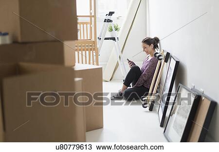 Stock Image - Young woman moving into new flat. Fotosearch