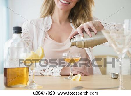 Stock Image - Young woman pouring coctail. Fotosearch