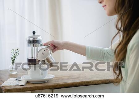 Young woman pouring milk into coffee cup View Large Photo Image Stock Photo - Young woman pouring milk into coffee cup. Fotosearch