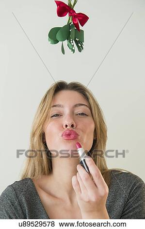 Stock Photo - Young woman puckering under mistletoe. Fotosearch