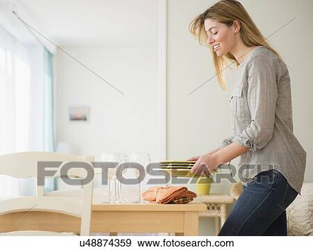 Stock Photo - Young woman setting table. Fotosearch
