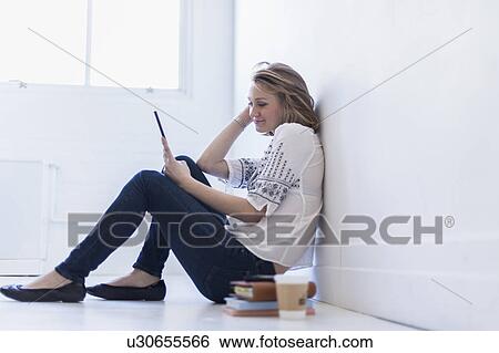 Young woman sitting on floor and using digital tablet View Large Photo Image Stock Photograph - Young woman sitting on floor and using digital tablet. Fotosearch