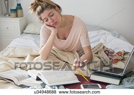 Stock Photo - Young woman studing in bed. Fotosearch