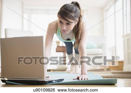 Young woman using laptop during exercising View Large Photo Image Stock Photograph - Young woman using laptop during exercising. Fotosearch