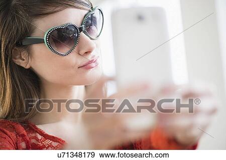 Stock Photo - Young woman wearing heart shaped sunglasses. Fotosearch