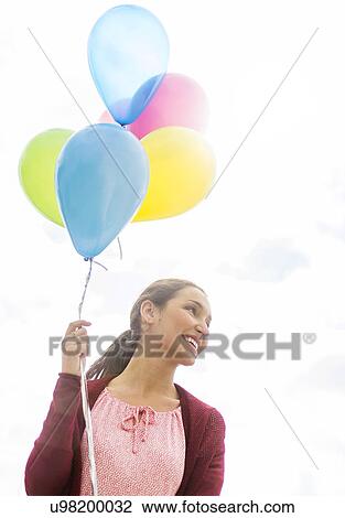 Stock Image - Young woman with colorful balloons. Fotosearch