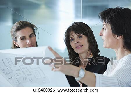 Stock Photography - Architects holding up blueprints for client in office. Fotosearch