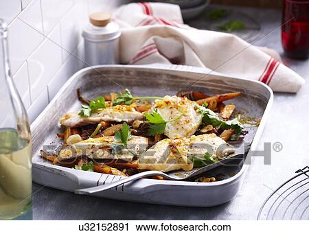 Stock Image - Baking tin with roast snapper with herb garnish. Fotosearch