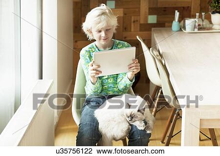 Boy with cat on his lap using digital tablet in kitchen View Large Photo Image Stock Image - Boy with cat on his lap using digital tablet in kitchen. Fotosearch