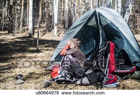 Boy with hands over his face sitting outside tent in forest View Large Photo Image Stock Photo - Boy with hands over his face sitting outside tent in forest. Fotosearch