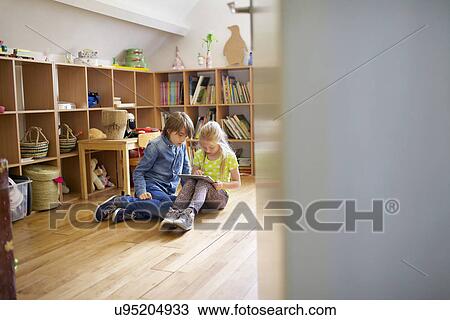 Stock Image - Brother and sister sharing and using digital tablet. Fotosearch