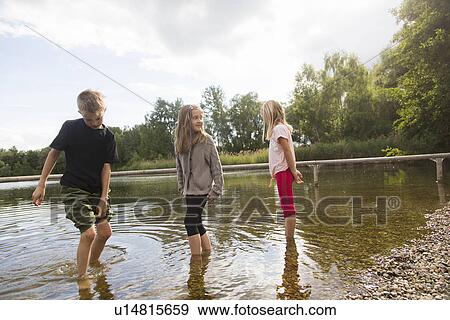 Brother and two sisters paddling in lake View Large Photo Image Stock Photo - Brother and two sisters paddling in lake. Fotosearch