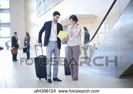 Businessman and businesswoman arriving in conference centre atrium View Large Photo Image Picture - Businessman and businesswoman arriving in conference centre atrium. Fotosearch