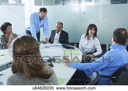 Businessmen and women chatting around boardroom table View Large Photo Image Stock Photography - Businessmen and women chatting around boardroom table. Fotosearch