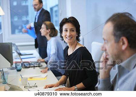 Businesspeople sitting at desk View Large Photo Image Stock Image - Businesspeople sitting at desk. Fotosearch