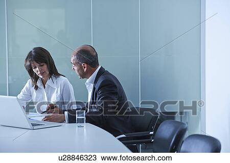Businesswoman and man doing paperwork at boardroom table View Large Photo Image Stock Image - Businesswoman and man doing paperwork at boardroom table. Fotosearch