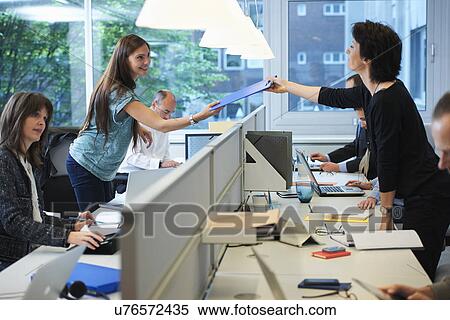 Businesswoman passing paperwork across screen partition in office View Large Photo Image Stock Photography - Businesswoman passing paperwork across screen partition in office. Fotosearch