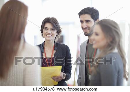 Stock Photo - Businesswomen and man with paperwork in conference centre atrium. Fotosearch