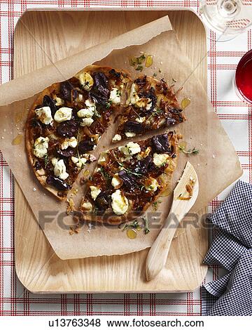 Stock Photo - Caramelized onion pizza on chopping board. Fotosearch