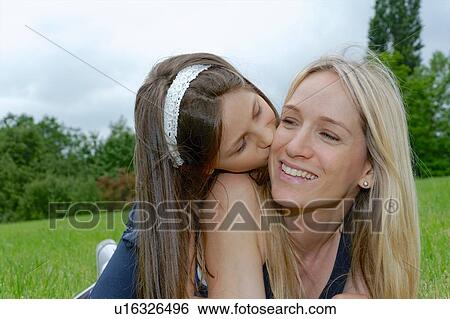 Close up of girl kissing mother on cheek in park View Large Photo Image Stock Photograph - Close up of girl kissing mother on cheek in park. Fotosearch