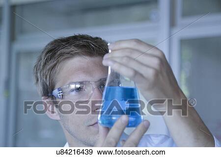 Close up of male scientist holding up erlenmeyer flask in lab View Large Photo Image Stock Photo - Close up of male scientist holding up erlenmeyer flask in lab. Fotosearch
