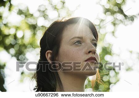 Stock Photograph - Close up portrait of serene young woman in park. Fotosearch
