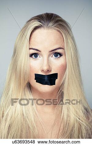 Stock Photo - Close up studio portrait of mid adult woman with adhesive tape over her mouth. Fotosearch