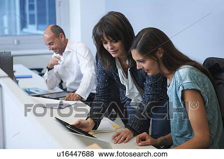 Stock Photo - Colleagues looking at digital tablet. Fotosearch