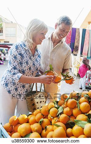 Stock Image - Couple choosing oranges at market, Mallorca, Spain. Fotosearch